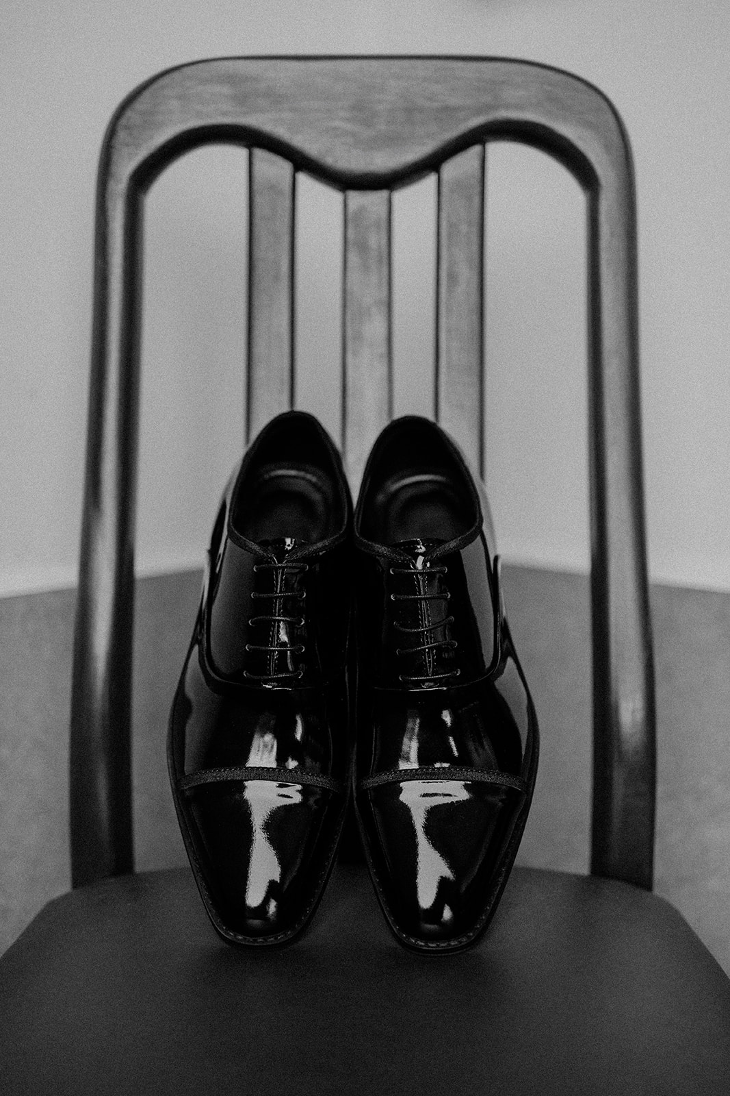 glossy black wedding shoes on a wooden chair