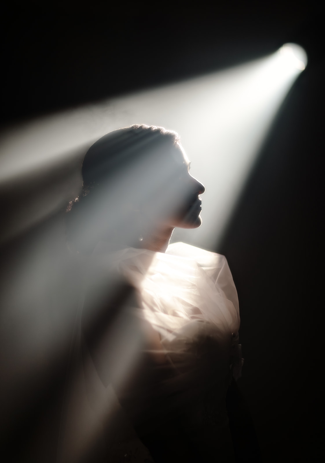 A wedding photograph of ray of light falling on the bride highlighting and enhancing the silhouette of the brides face
