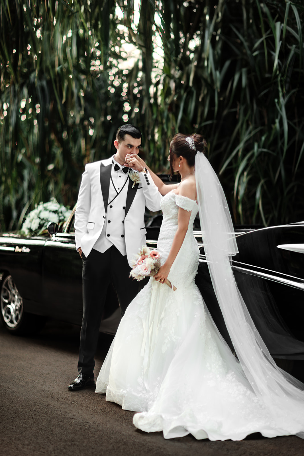 a wedding portrait of a bride and a groom infant of a vintage car
